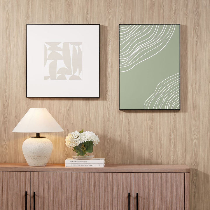 The wall above the wooden cabinet features two decorative picture frames hung with a picture hanger for a damage-free setup.