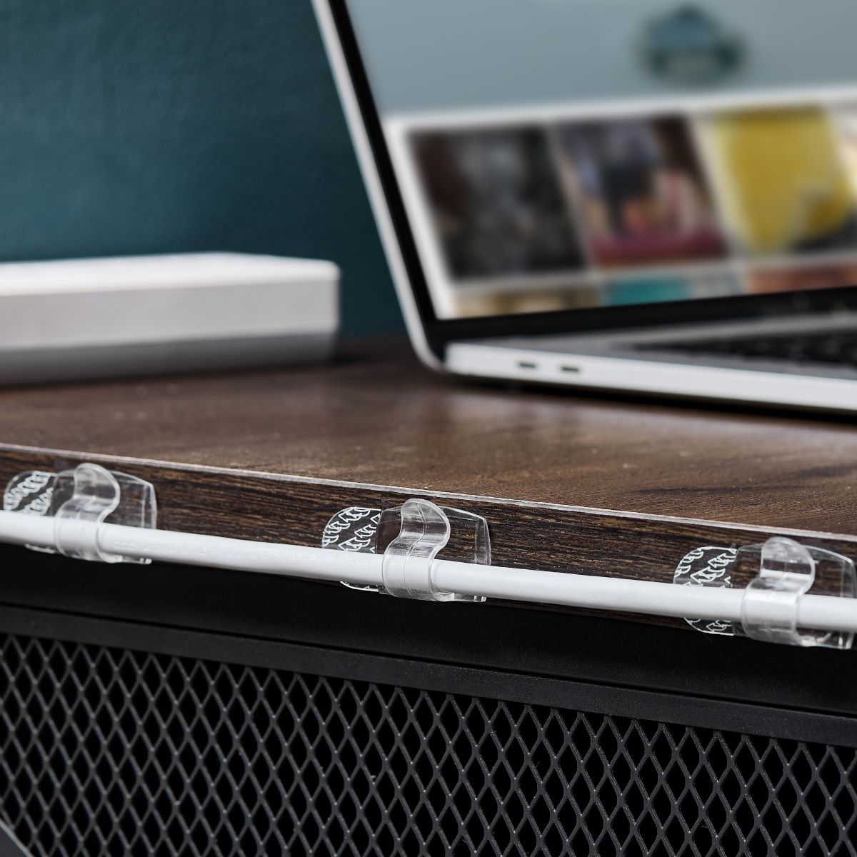 Three large clips secure the cables along the edge of the desk, keeping everything neat and organized.