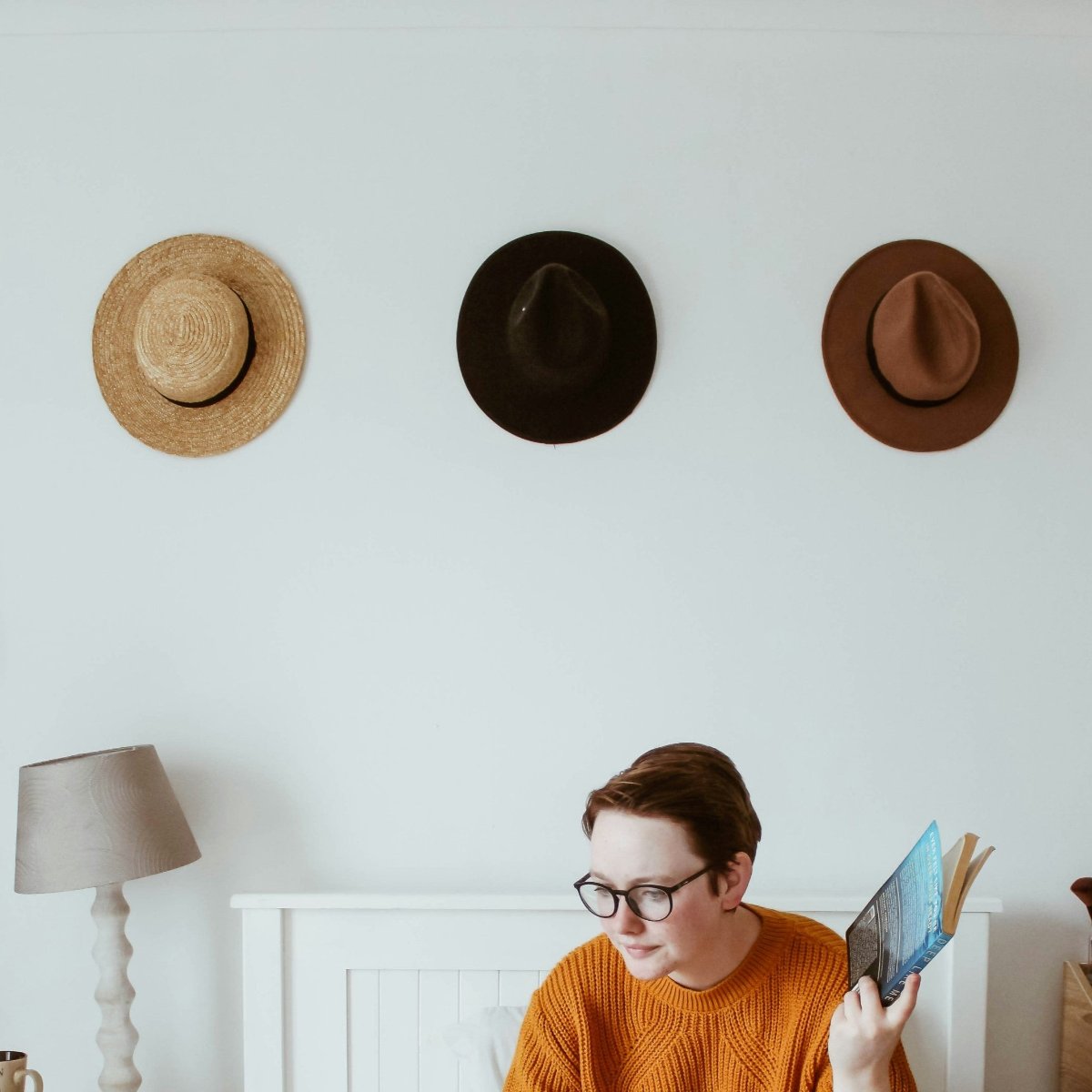 Three large utility hooks on the wall are used to hang three hats.