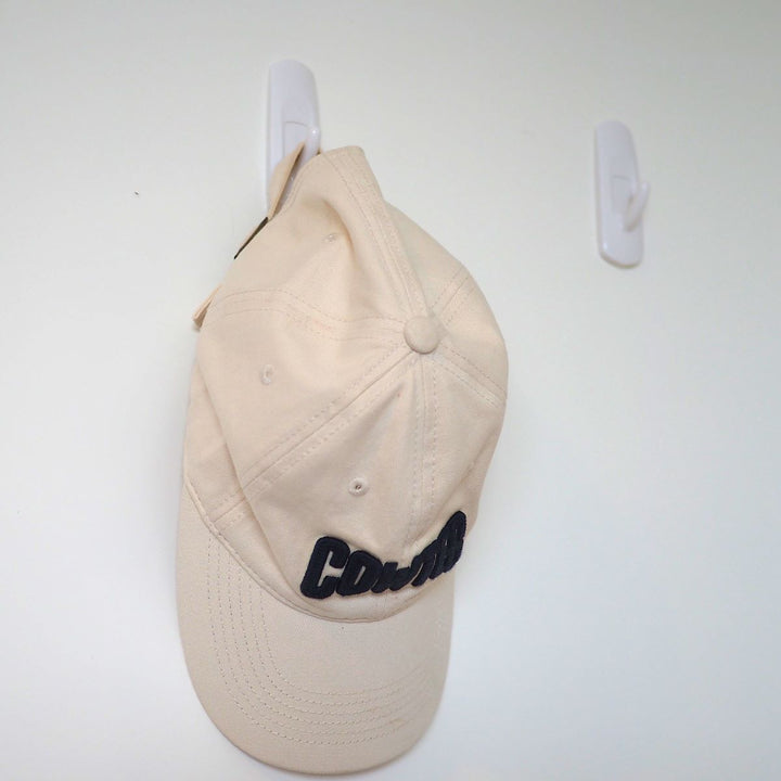 The wall features two Medium Utility Hooks, one of which is holding a baseball cap. These hooks are removable for convenience.