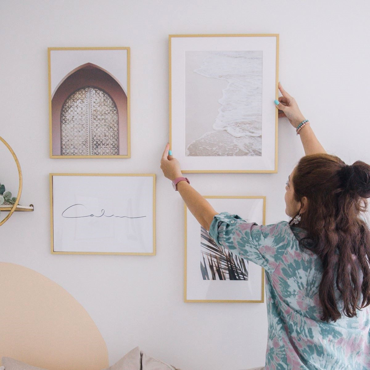 a woman hanging picture on the wall without tools