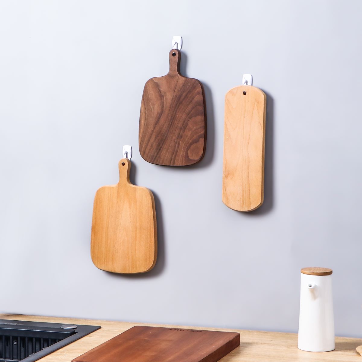 heavy-duty hooks glued to the wall hung three different sized chopping boards